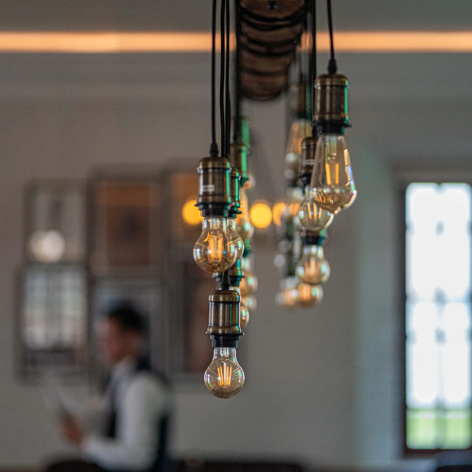 Un luminaire suspendu avec plusieurs ampoules allumées dans un intérieur flou