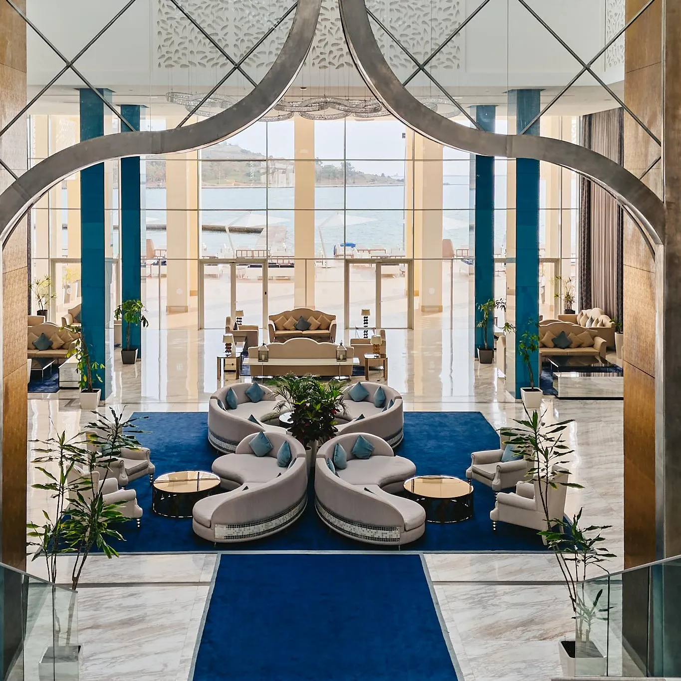 Un espace intérieur luxueux avec des canapés modulaires, des plantes vertes et une vue sur la mer à travers de grandes baies vitrées