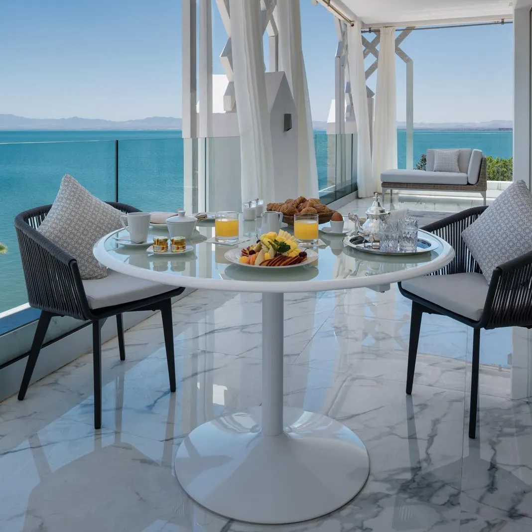 Une table avec un petit-déjeuner est installée sur un balcon avec vue sur la mer