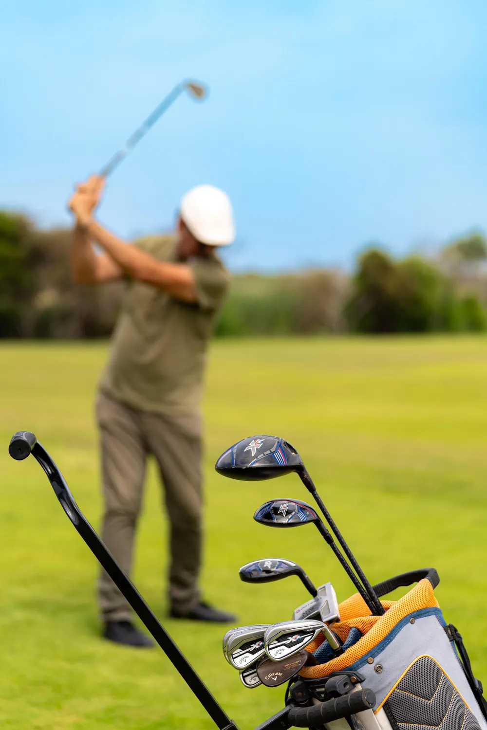 Un golfeur en action sur un green avec un sac de clubs à proximité