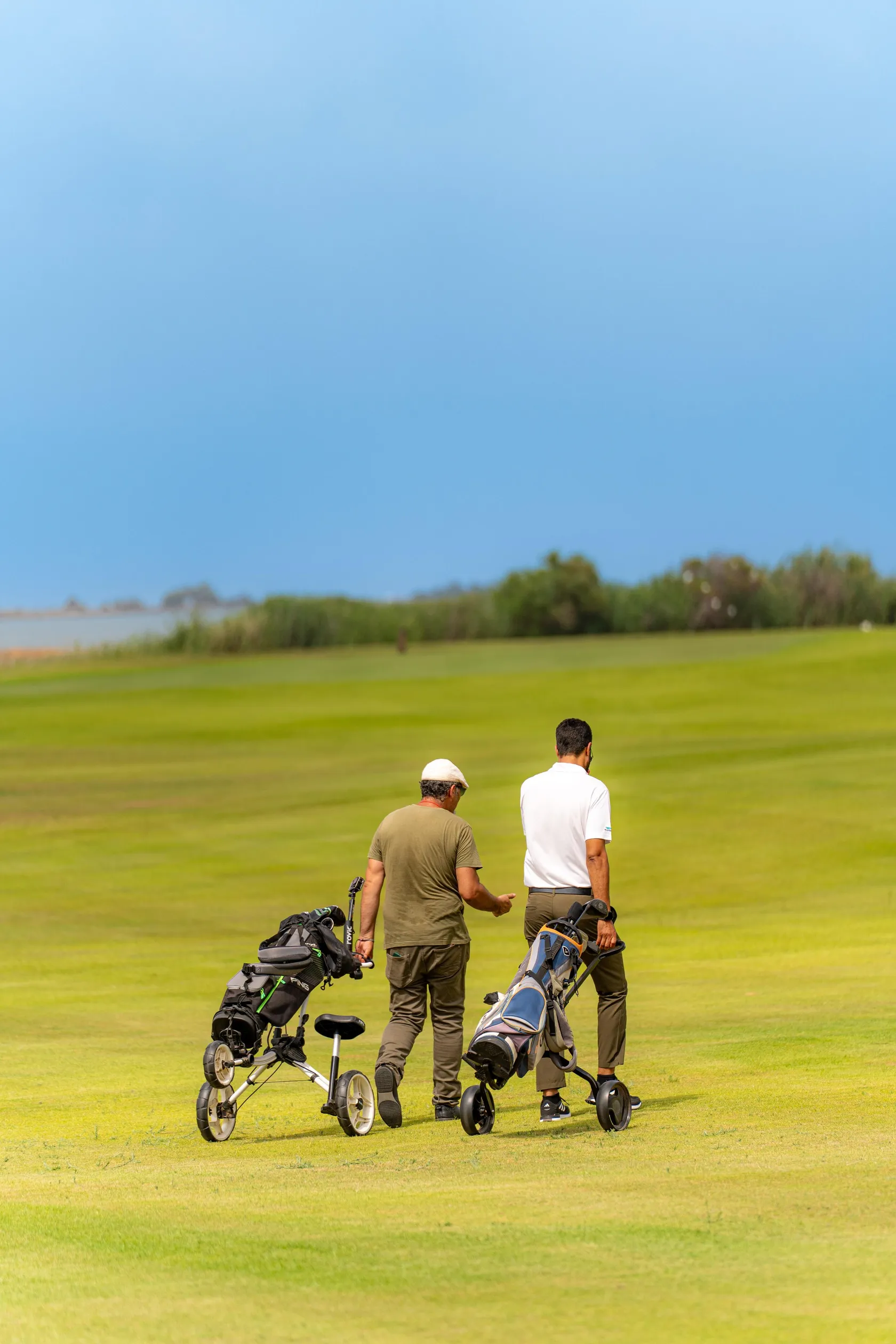 Deux hommes discutent sur un terrain de golf avec leurs chariots de clubs