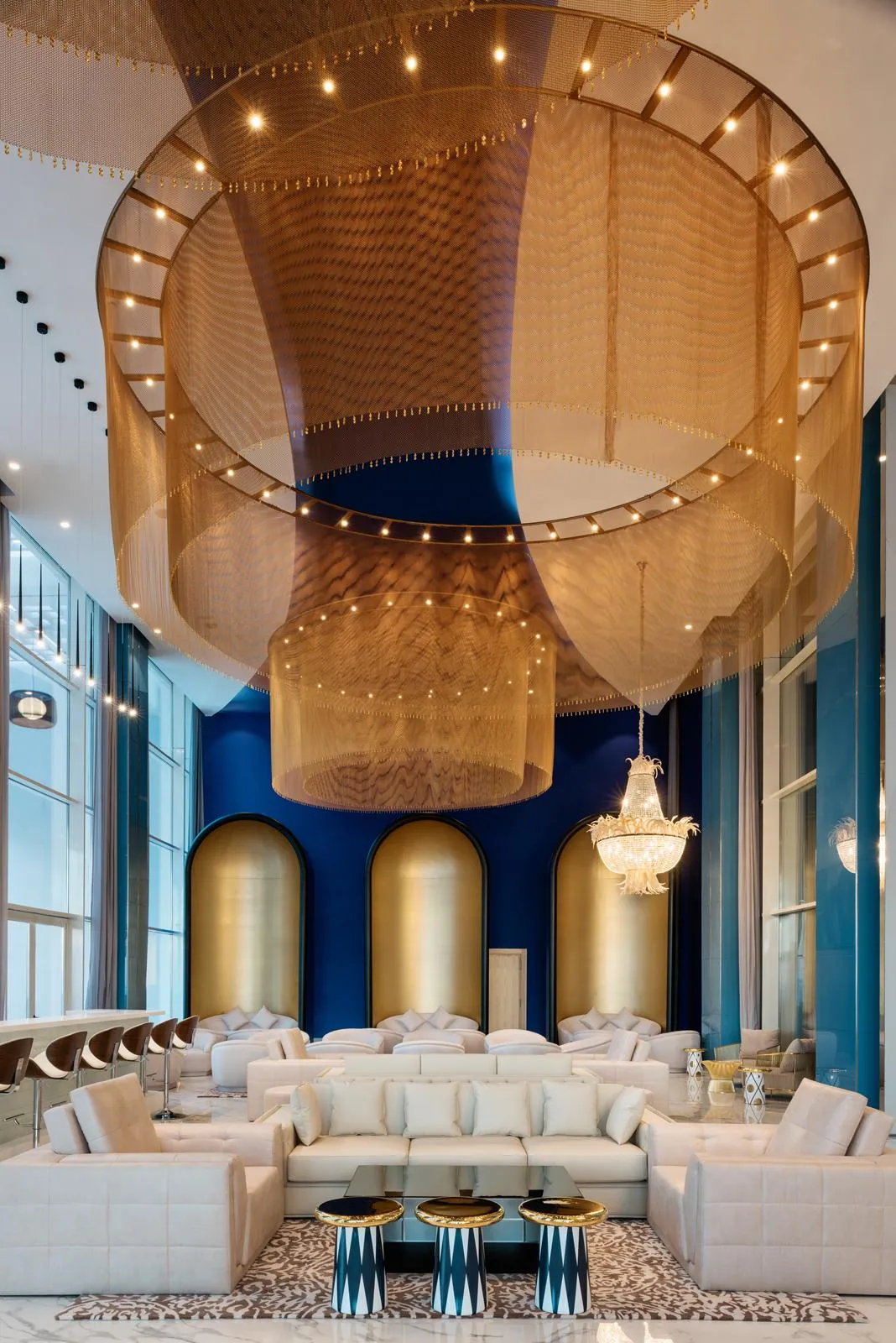 Un salon luxueux avec des canapés blancs, des tables basses et un plafond décoré de tissus dorés et de lumières
