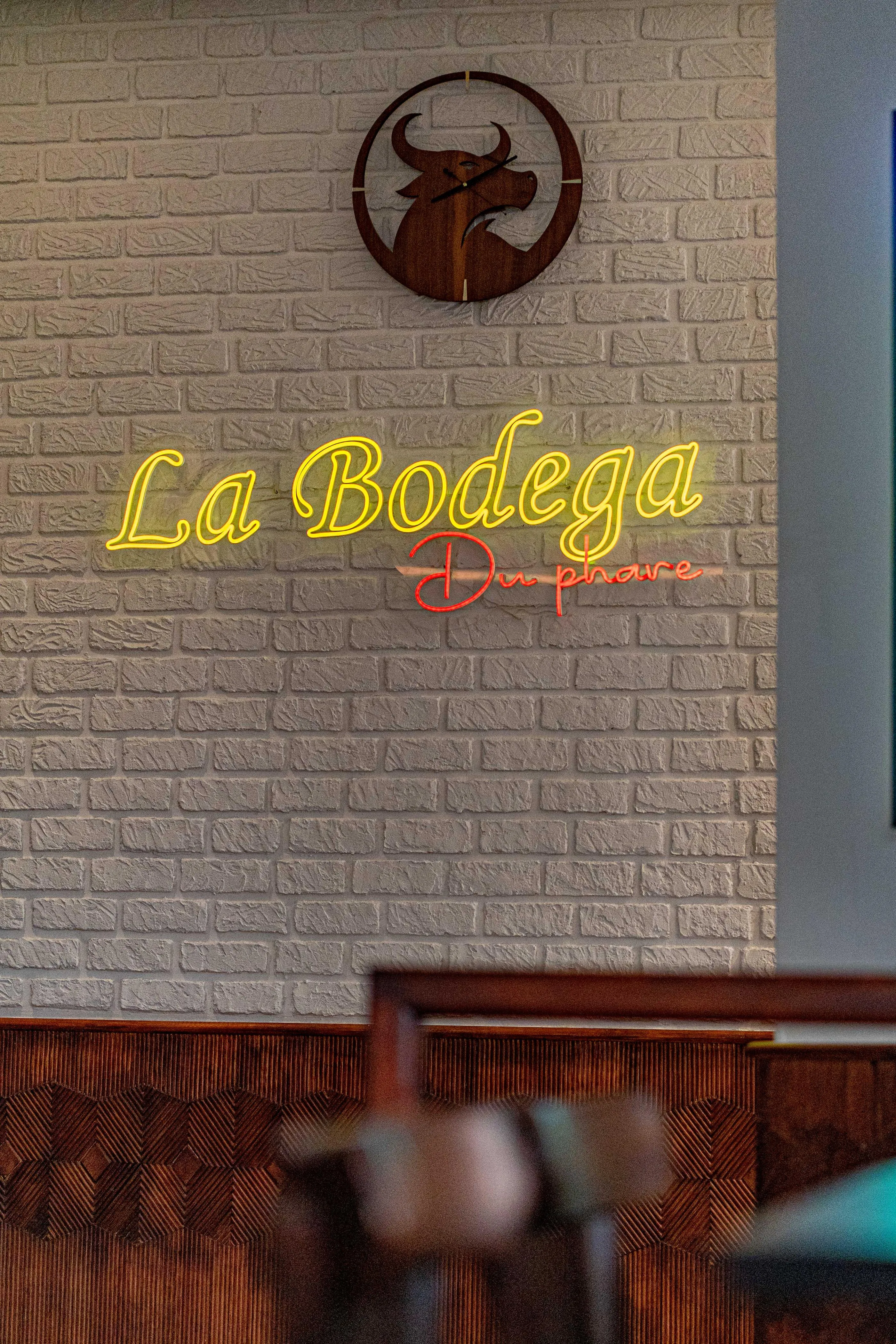 Mur de briques avec l'enseigne lumineuse "La Bodega" et un logo de taureau au-dessus