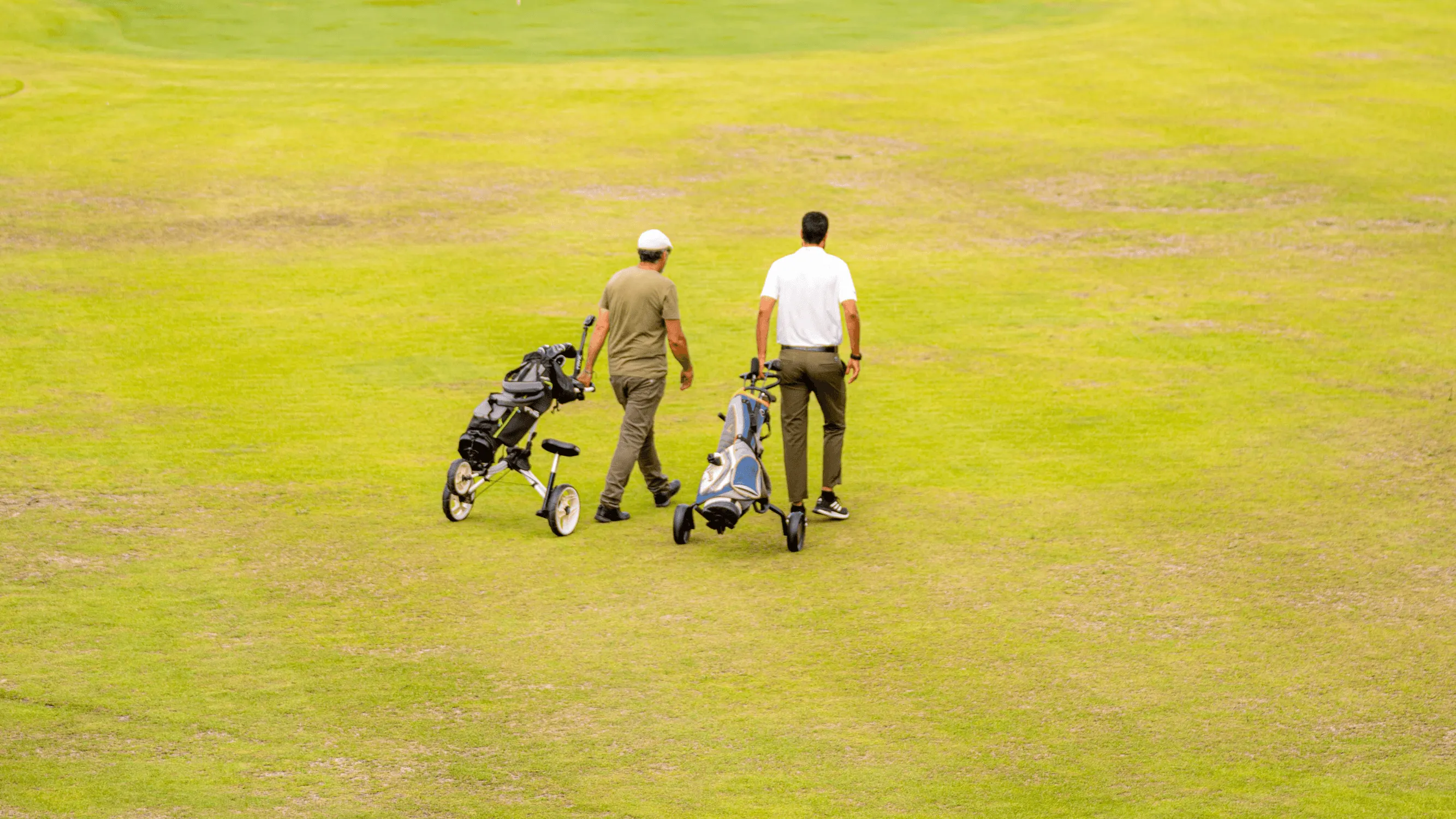 Deux personnes marchent sur un terrain de golf en poussant des chariots de clubs