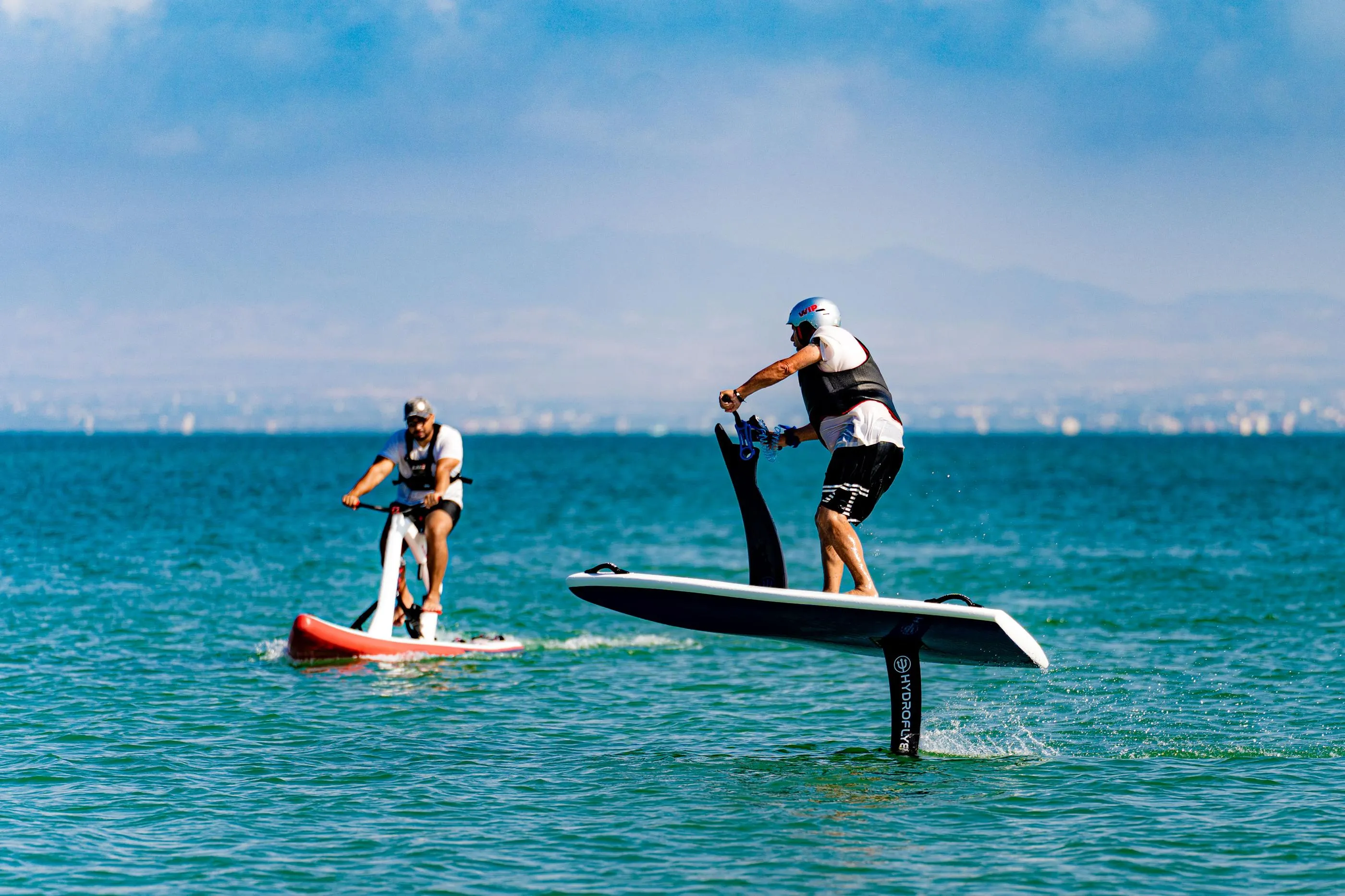 Deux personnes font du paddleboard sur une étendue d'eau avec un fond de ville lointain