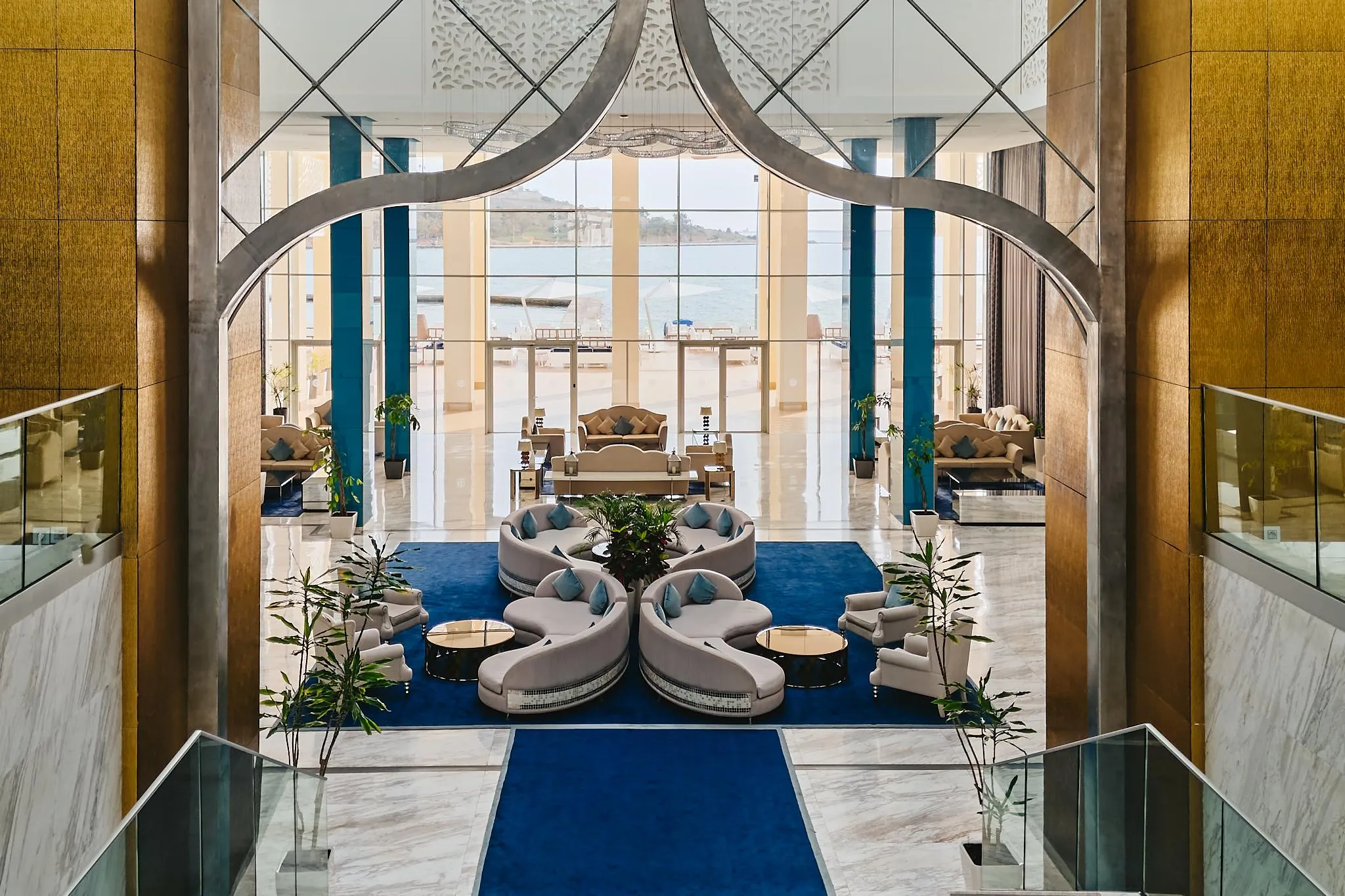 Un espace intérieur luxueux avec des canapés modulaires, des plantes vertes et une vue sur la mer à travers de grandes baies vitrées