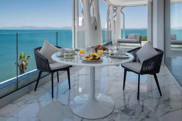Une table avec un petit-déjeuner est installée sur un balcon avec vue sur la mer